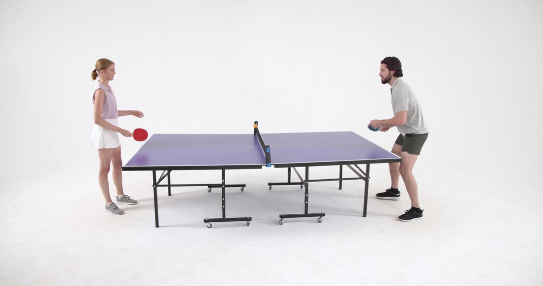 Man and Woman Competing in Table Tennis Match in Modern Studio