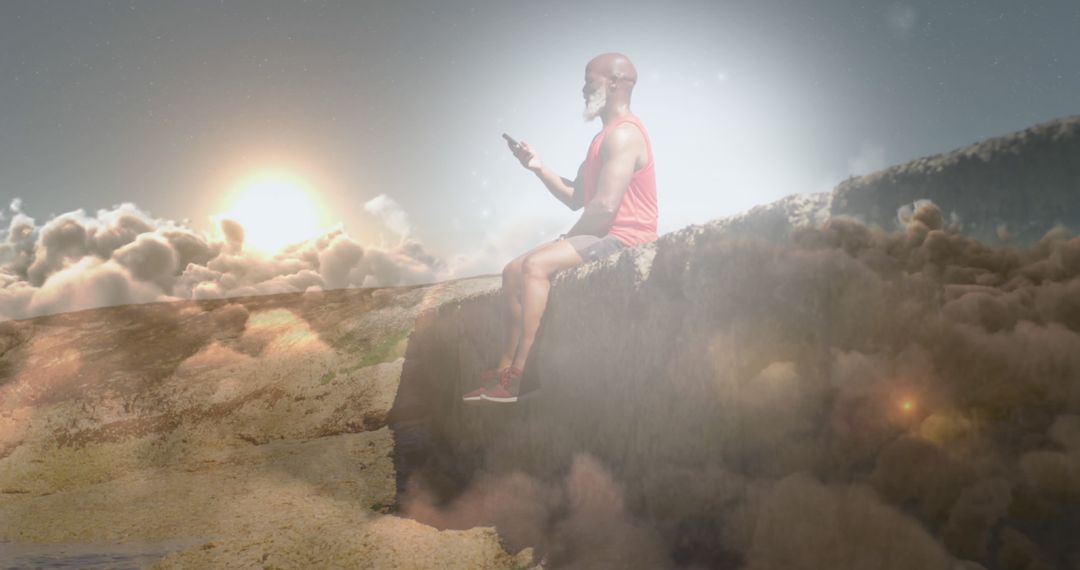 Man Sitting on Edge of Cliff Above Clouds Using Smartphone - Free Images, Stock Photos and Pictures on Pikwizard.com