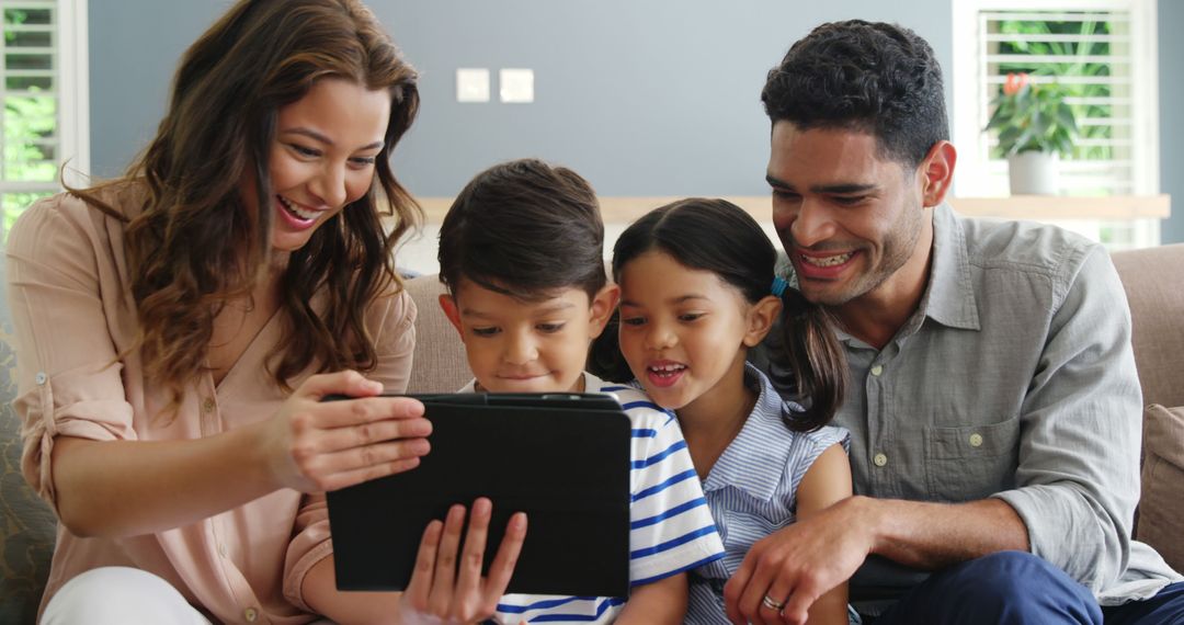 Happy Family Smiling While Using Digital Tablet In Living Room - Free Images, Stock Photos and Pictures on Pikwizard.com