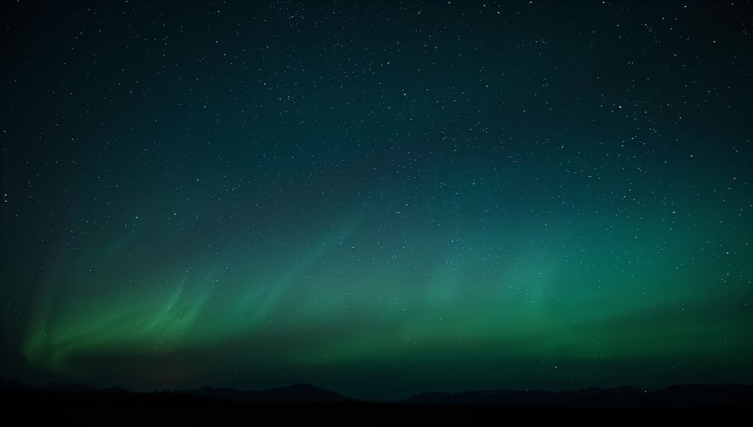 Dancing aurora borealis sweeping across starry northern sky over silhouetted mountains