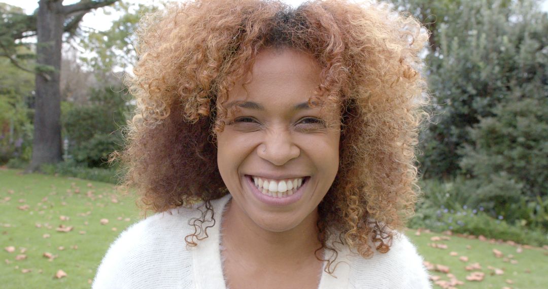 Smiling Woman with Curly Hair Enjoying a Day Outdoors - Free Images, Stock Photos and Pictures on Pikwizard.com