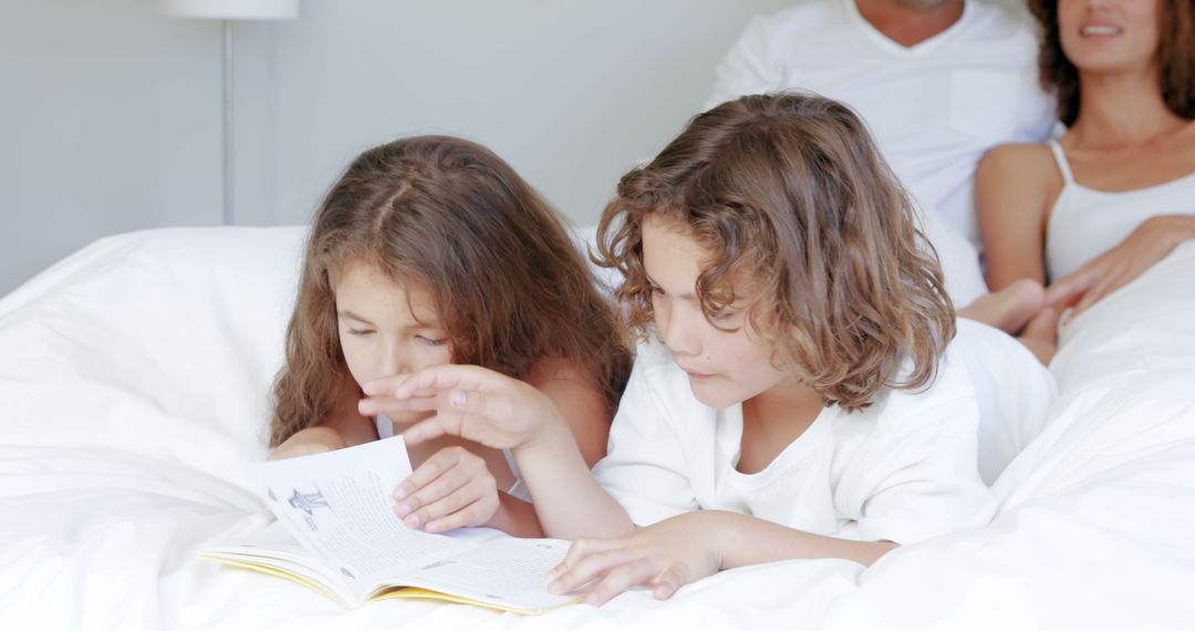 Children Reading Storybook in Bed with Parents Nearby - Free Images, Stock Photos and Pictures on Pikwizard.com