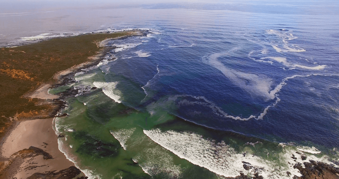 Transparent Ocean Waves Meeting Rugged Coastline Aerial View