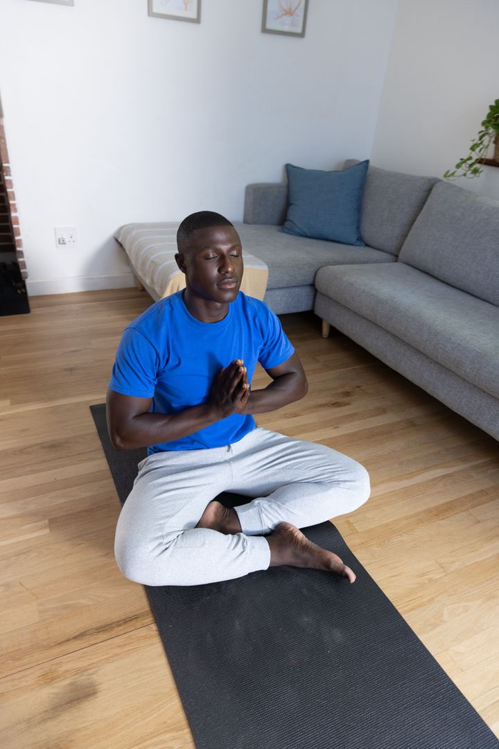 African American Man Meditating on Yoga Mat at Home