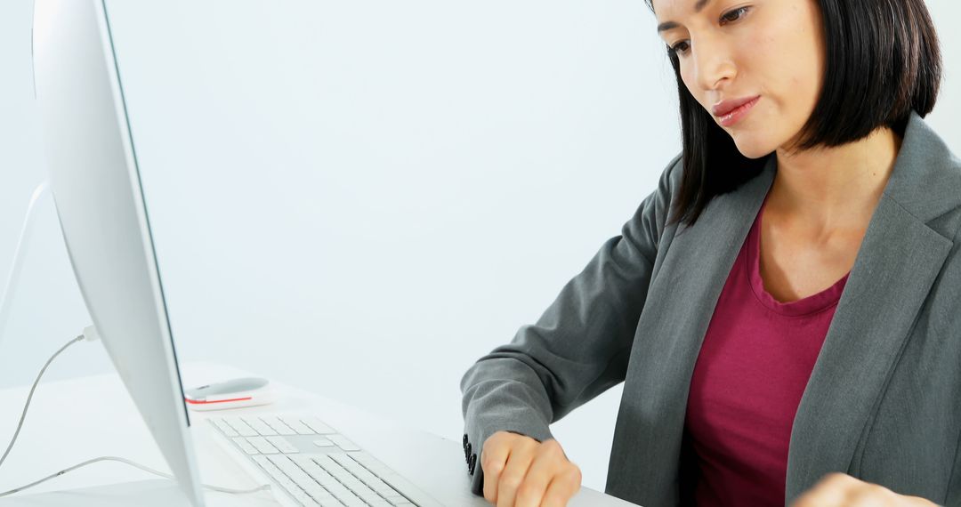 A young Asian businesswoman is focused on her work at a computer, with copy space - Free Images, Stock Photos and Pictures on Pikwizard.com