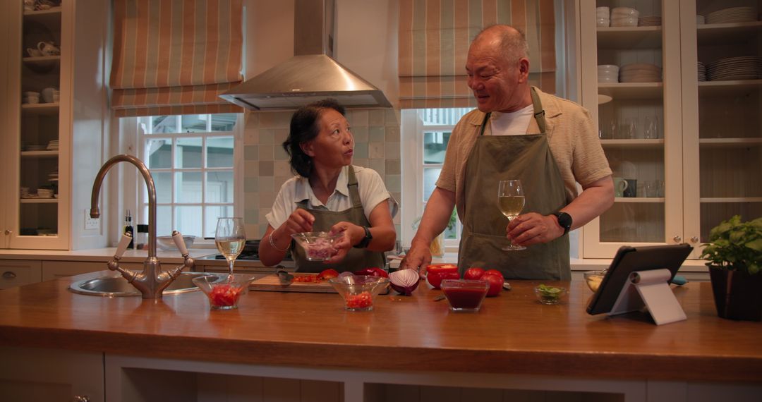 Senior Couple Cooking Together at Home Enjoying Wine