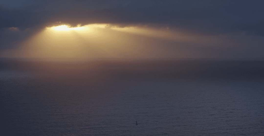 Transparent Sun Beams through Cloudy Sky over Serene Sea