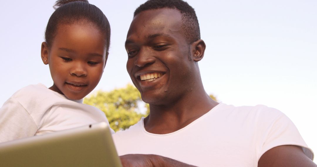 Smiling Father and Daughter Using Tablet Outdoors - Free Images, Stock Photos and Pictures on Pikwizard.com