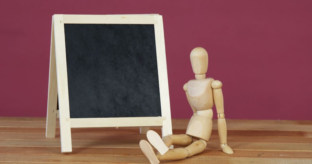 Wooden Mannequin Figure Sitting by Chalkboard Easel - Free Images, Stock Photos and Pictures on Pikwizard.com