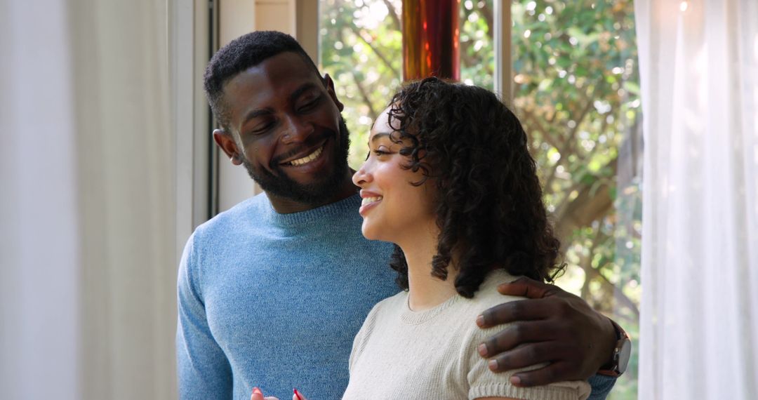 Diverse Couple Smiling by Window in Cozy Home