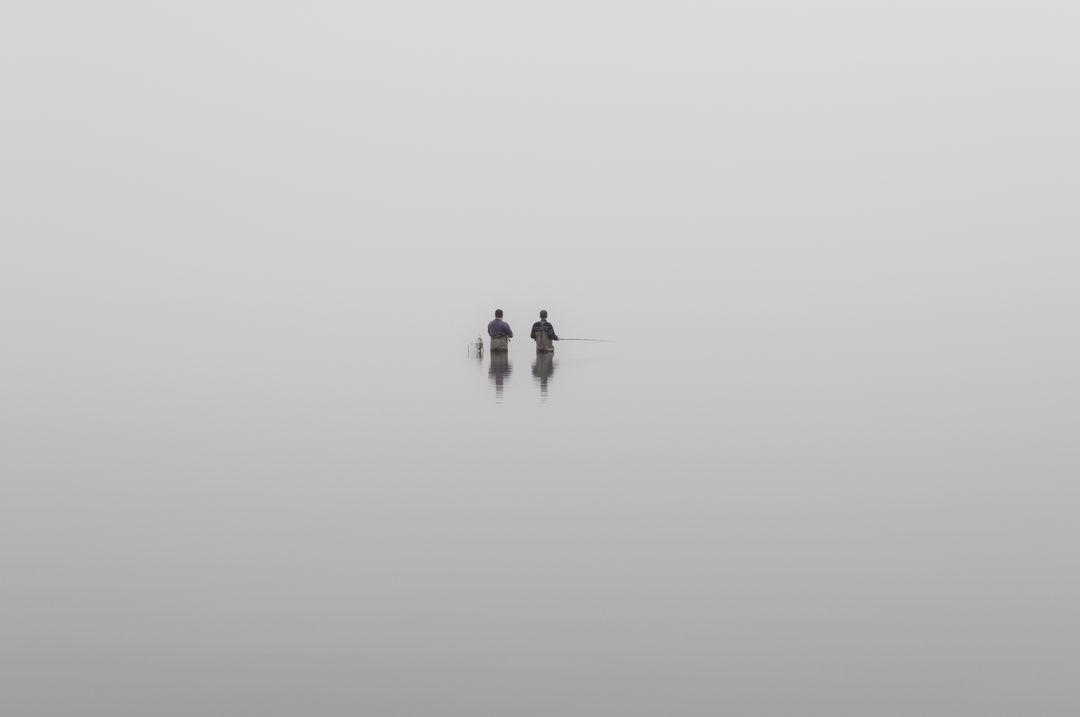 Two People Standing in Calm, Misty Water Creating a Serene Reflection - Free Images, Stock Photos and Pictures on Pikwizard.com