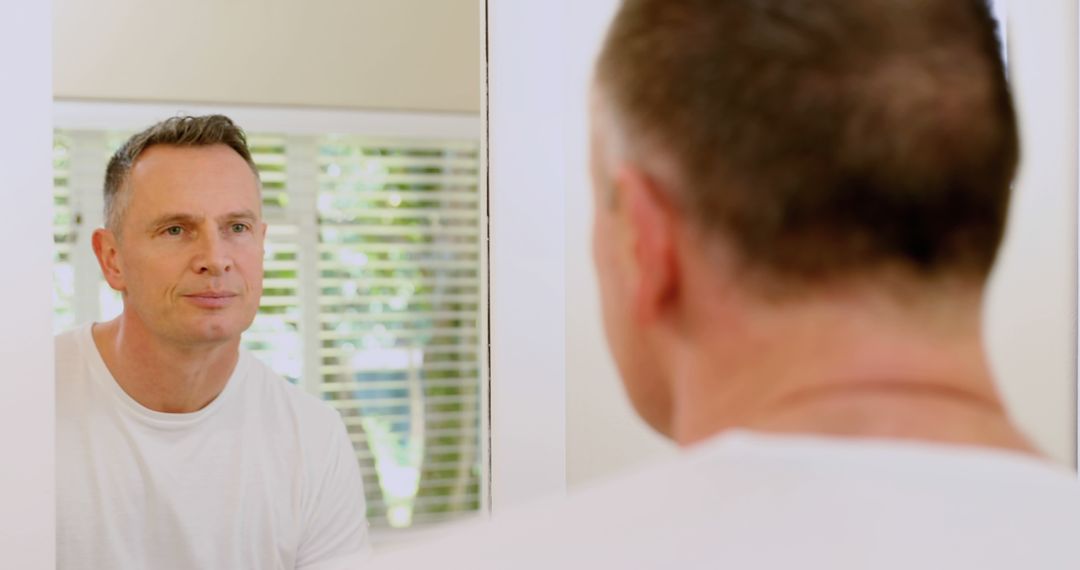 Middle-aged man looking in bathroom mirror with thoughtful expression - Free Images, Stock Photos and Pictures on Pikwizard.com