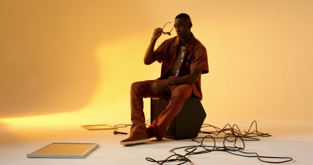 Man Sitting on Speaker with Sunglasses in Stylish Studio