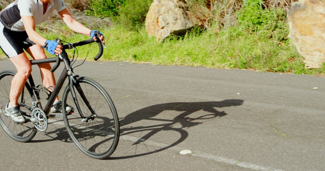 Cyclist Riding on Sunlit Road in Nature - Free Images, Stock Photos and Pictures on Pikwizard.com