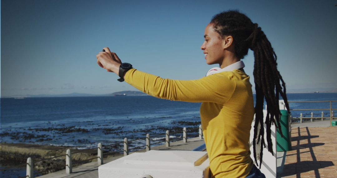 Smiling Woman Capturing Scenic Ocean View at Promenade