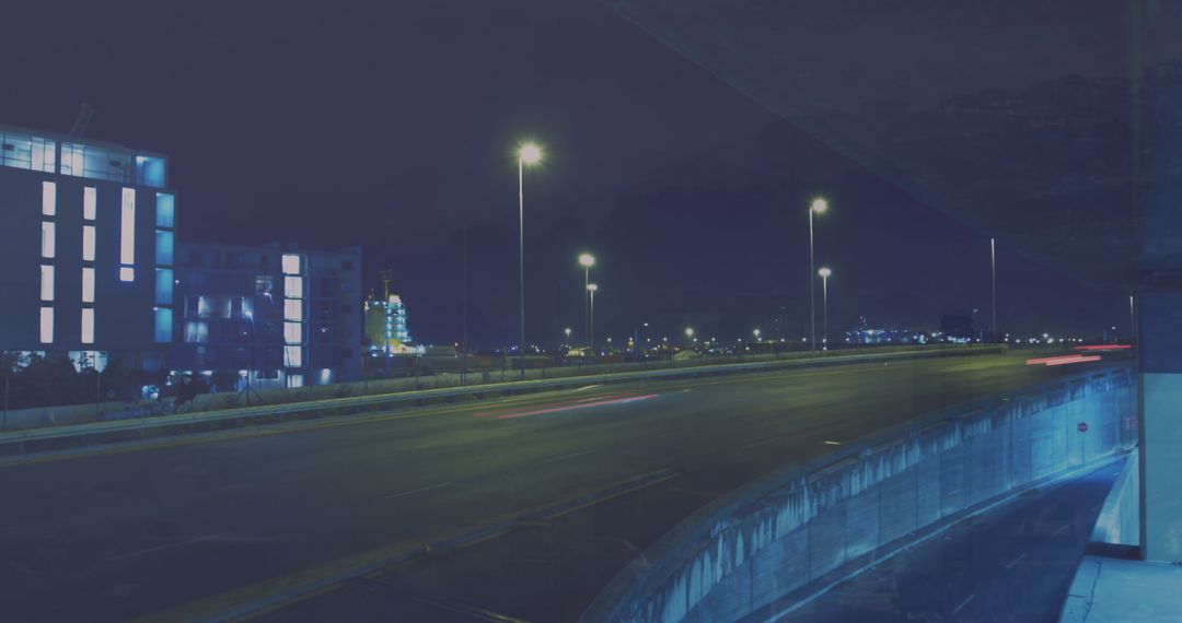 Night City Highway with Buildings Illuminated Against Dark Sky