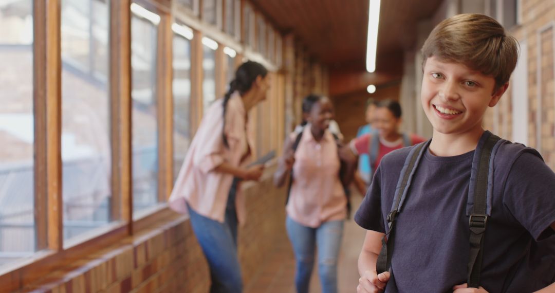 Smiling Boy in School Hallway with Classmates Studying in Background