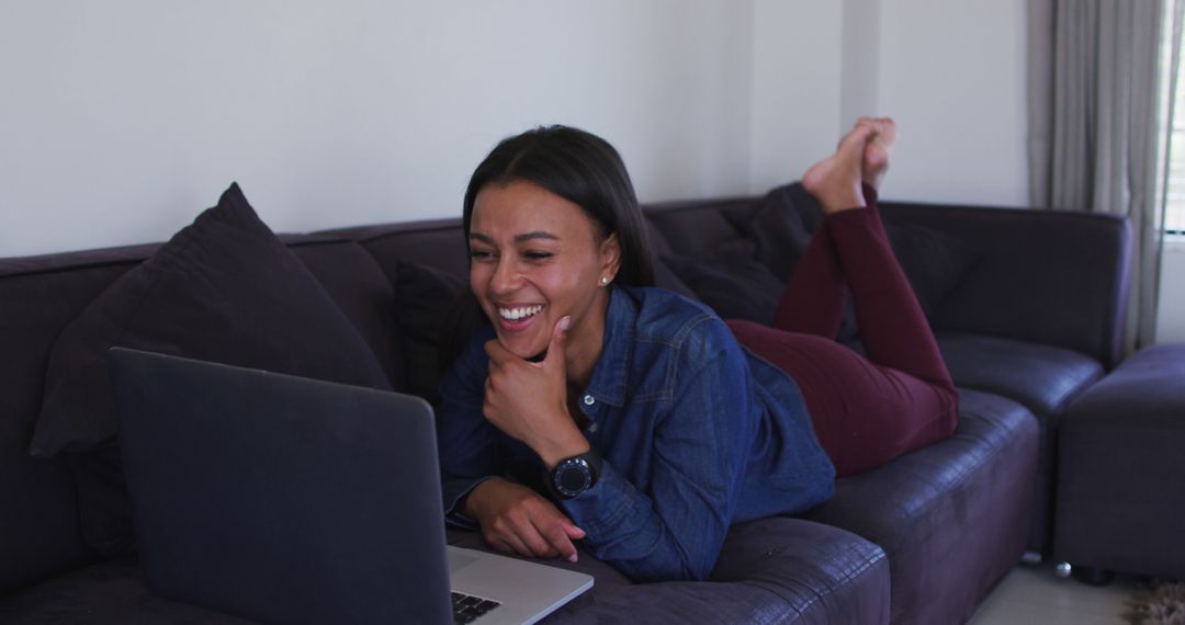 Woman Laughing While Watching Laptop on Couch at Home - Free Images, Stock Photos and Pictures on Pikwizard.com