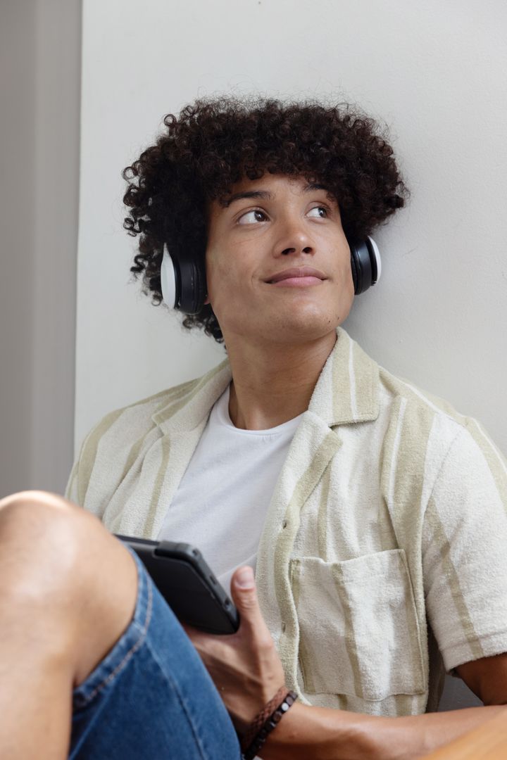Young Man with Headphones Sitting Relaxed with Smartphone at Home