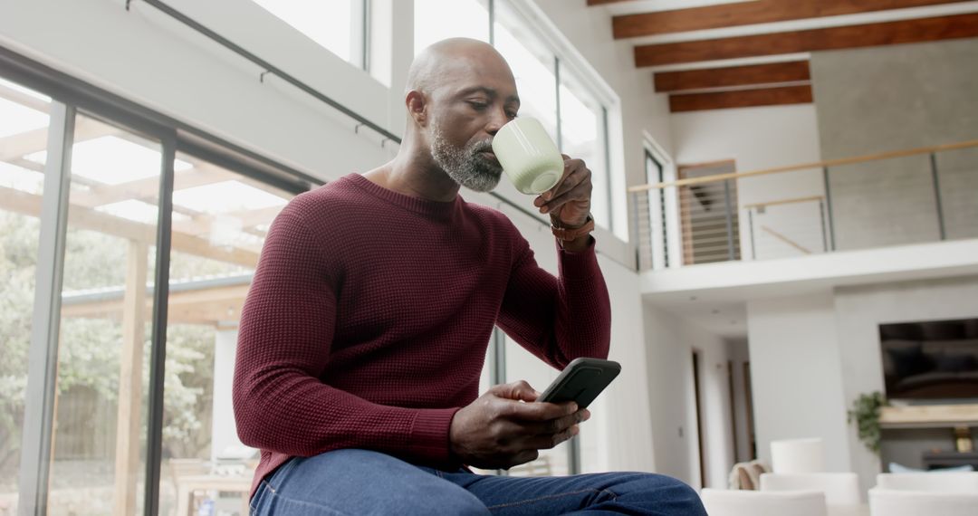 Mature Man Enjoying Coffee While Browsing Smartphone at Home - Free Images, Stock Photos and Pictures on Pikwizard.com