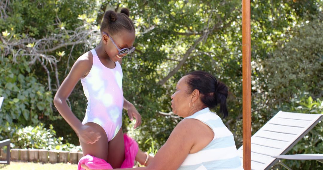Grandmother Wrapping Towel Around Granddaughter at Poolside