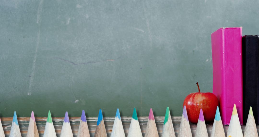 Colorful Pencils and School Books Against Chalkboard