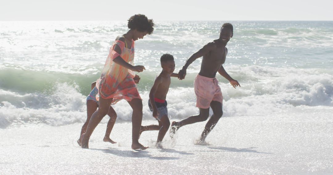 Smiling african american family holding hands and running on sunny beach - Free Images, Stock Photos and Pictures on Pikwizard.com