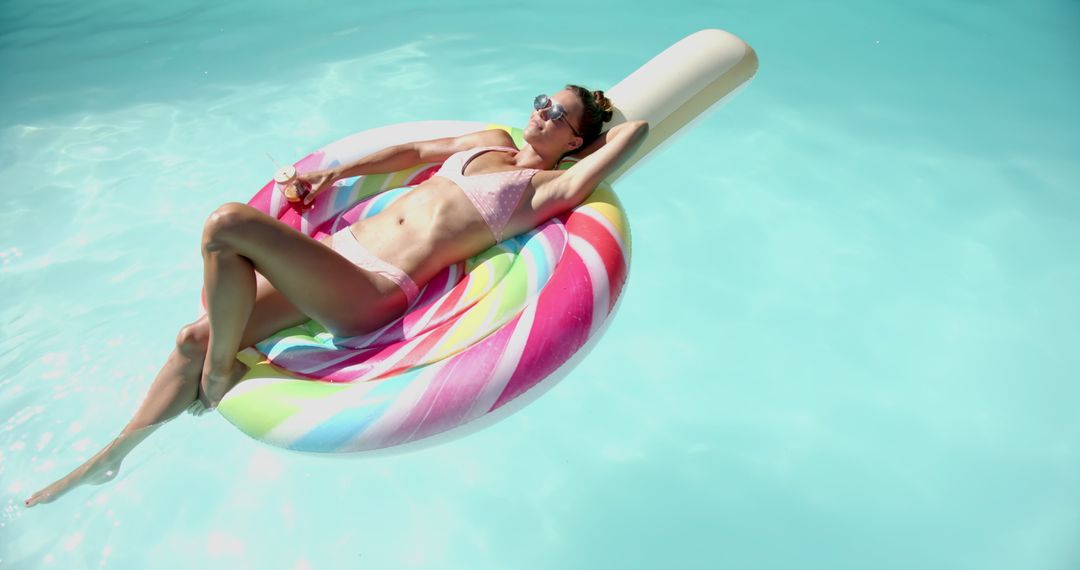 Woman Relaxing on Colorful Pool Float with Cocktail in Hand