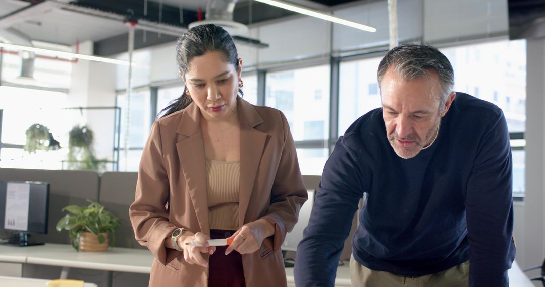 Diverse coworkers collaborating at modern office desk reviewing documents and screens