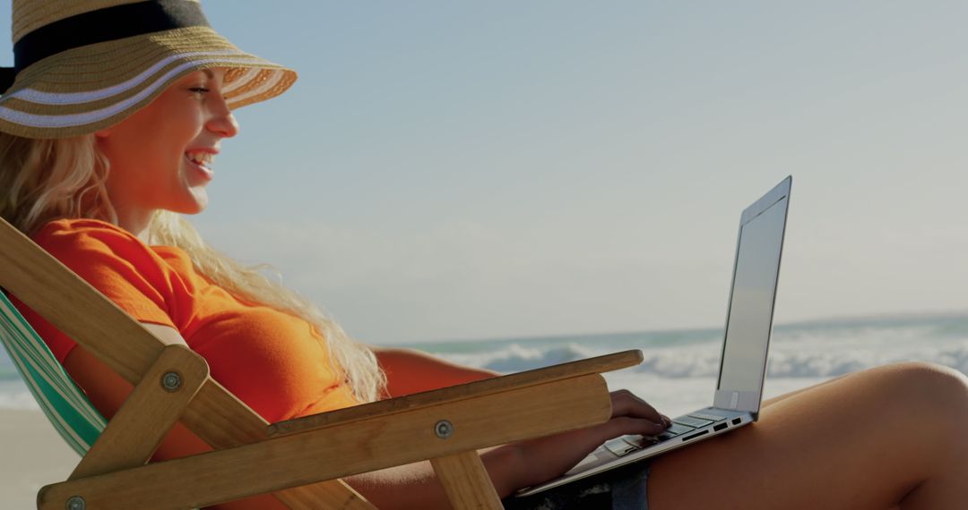 Young Woman Lounging at Beach Using Laptop Under Sun