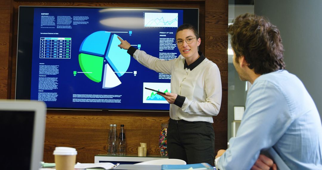Businesswoman Presenting Data to Colleague in Modern Office - Free Images, Stock Photos and Pictures on Pikwizard.com