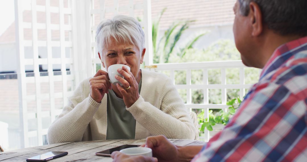 Senior Couple Enjoying Coffee Together on a Sunny Patio - Free Images, Stock Photos and Pictures on Pikwizard.com