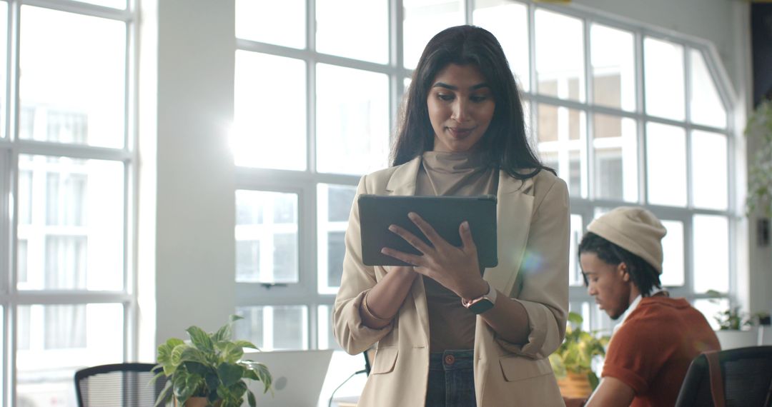 Modern coworking team collaborating in bright office using tablet and laptop