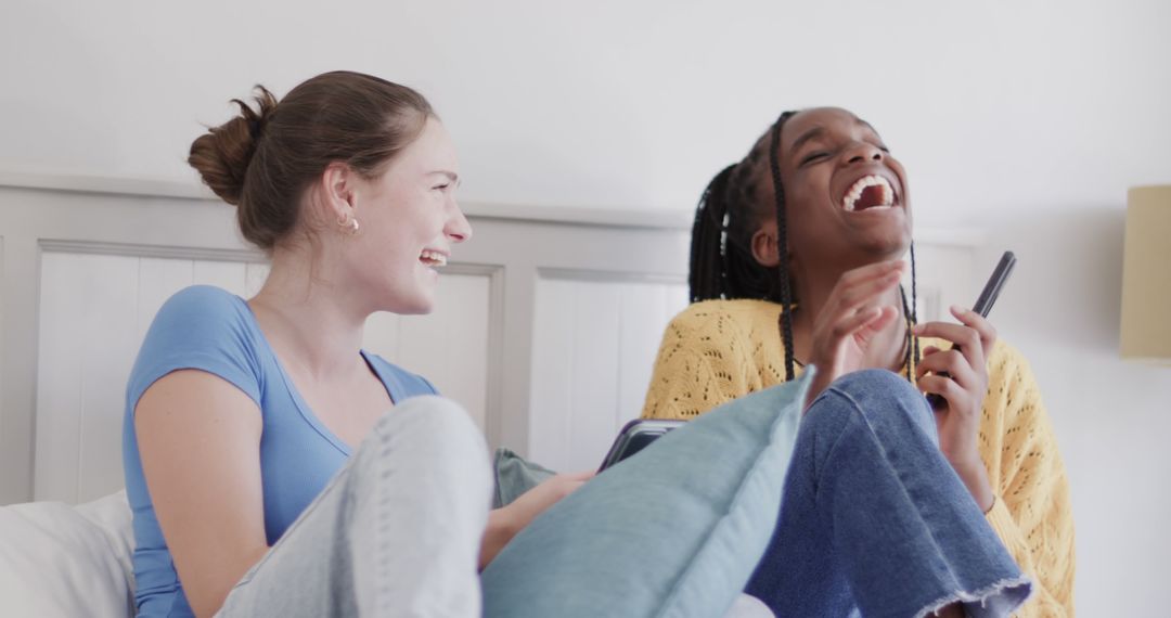 Teenage Girls Laughing and Using Smartphones Together in Bedroom - Free Images, Stock Photos and Pictures on Pikwizard.com