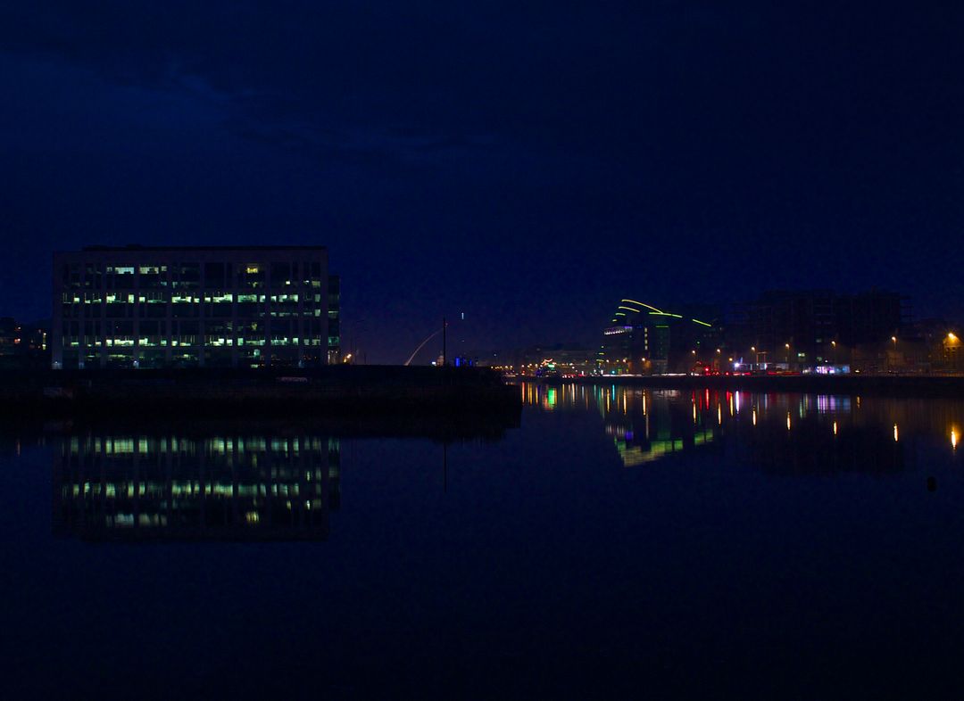 Cityscape reflection on calm river at night with illuminated buildings - Free Images, Stock Photos and Pictures on Pikwizard.com