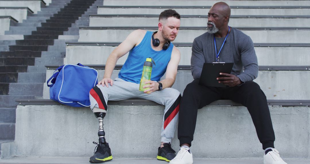 Athlete with Prosthetic Leg Listening to Coach in Stadium - Free Images, Stock Photos and Pictures on Pikwizard.com