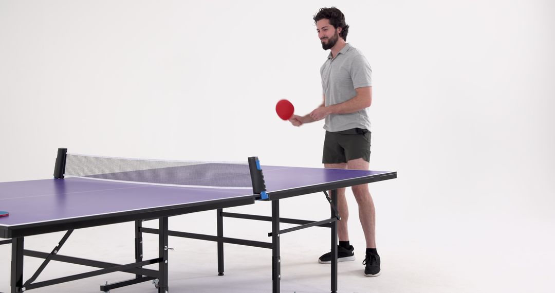 Man Preparing for Table Tennis Serve on Purple Ping Pong Table