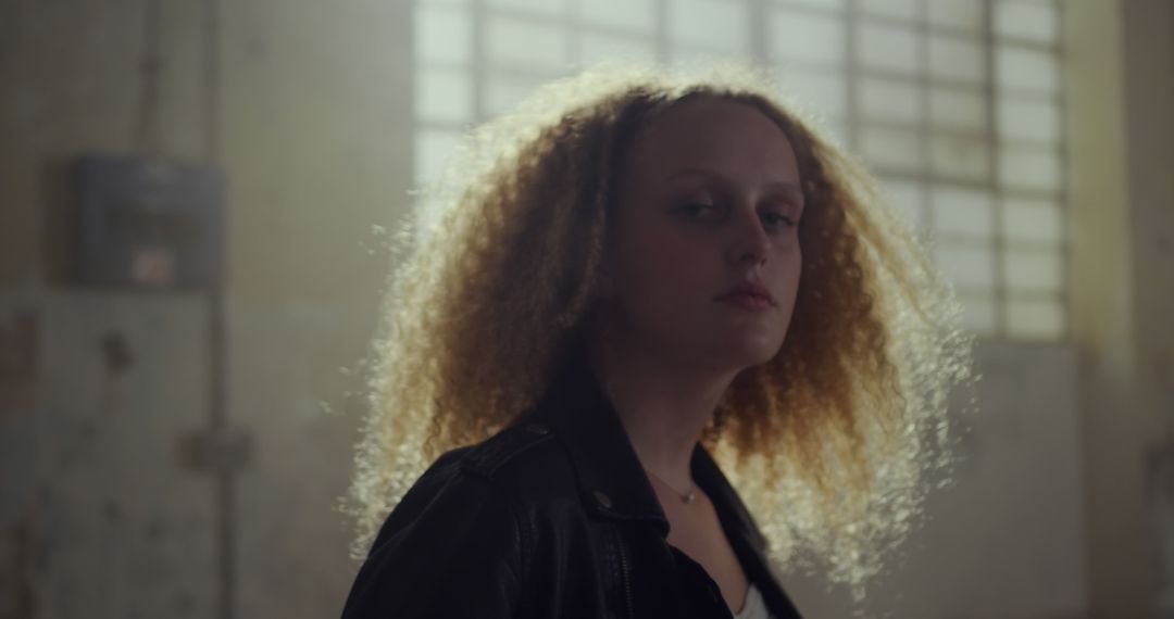 Confident Young Woman with Curly Hair in Leather Jacket Indoors - Free Images, Stock Photos and Pictures on Pikwizard.com