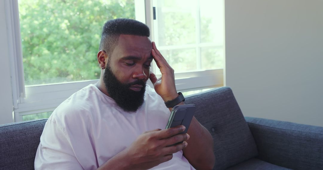 Pensive Man Holding Smartphone at Home Near Window