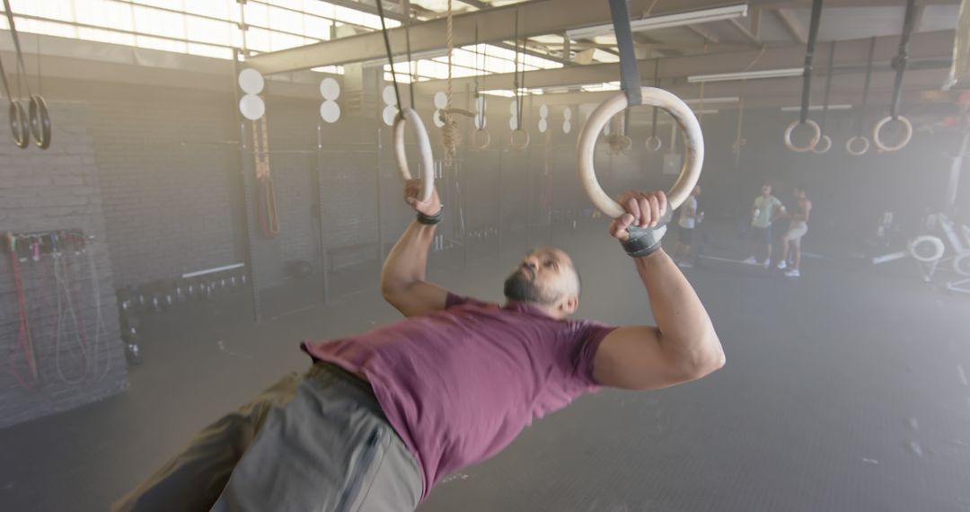 Man exercising on gymnastic rings in industrial gym - Free Images, Stock Photos and Pictures on Pikwizard.com