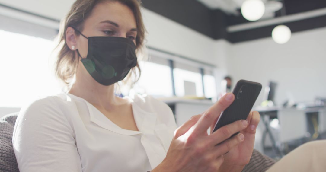 Woman Wearing Face Mask Using Smartphone in Modern Office - Free Images, Stock Photos and Pictures on Pikwizard.com