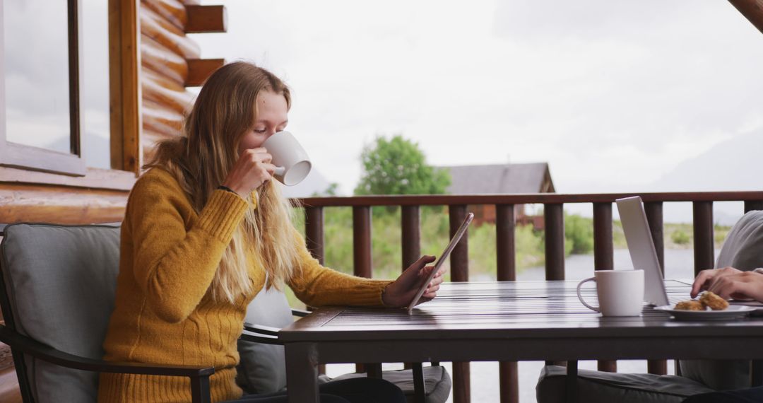 Young Woman Drinking Coffee and Using Digital Tablet on Wooden Terrace - Free Images, Stock Photos and Pictures on Pikwizard.com