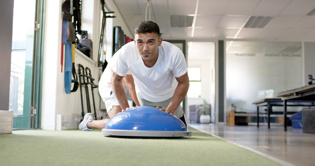 Focused Man Performing Push-ups on Balance Trainer in Rehabilitation Center