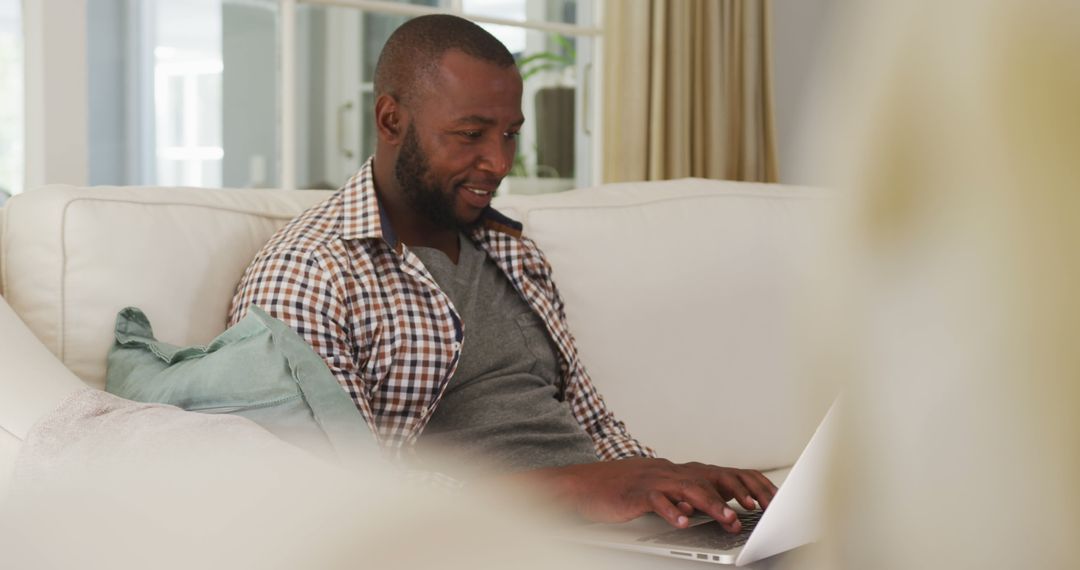 Smiling Man Using Laptop on Couch Working from Home - Free Images, Stock Photos and Pictures on Pikwizard.com