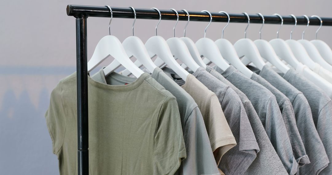 Neutral-colored plain t-shirts are displayed on white hangers, hinting at minimalism or retail. - Free Images, Stock Photos and Pictures on Pikwizard.com