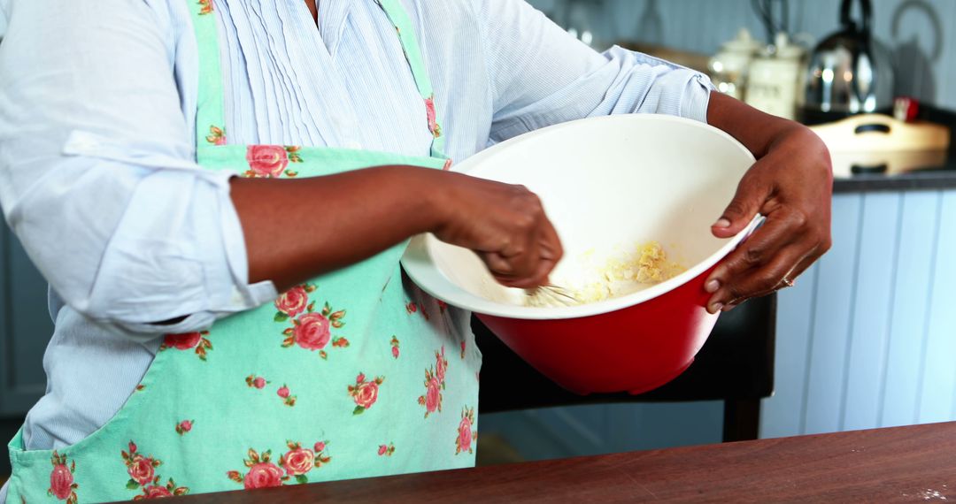 African American Woman Mixing Ingredients in Kitchen with Floral Apron - Free Images, Stock Photos and Pictures on Pikwizard.com