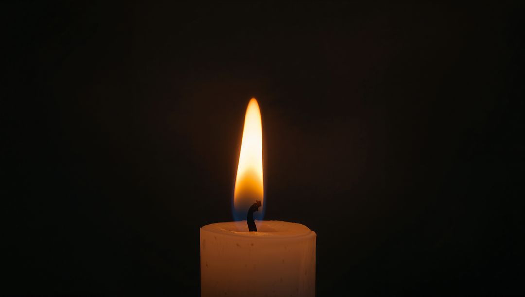 White candle burning with blue and amber flame casting soft halo