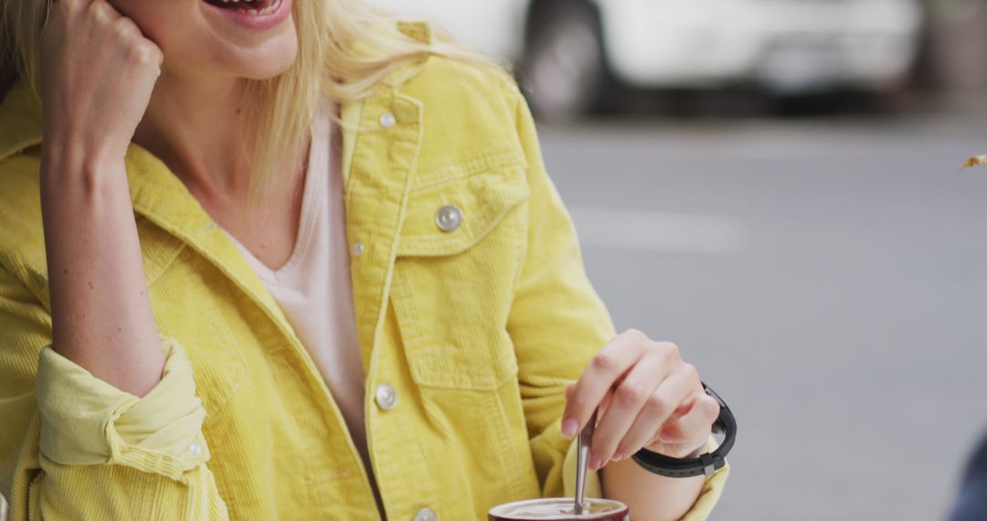 Smiling Woman in Yellow Jacket Enjoying a Drink Outdoors - Free Images, Stock Photos and Pictures on Pikwizard.com