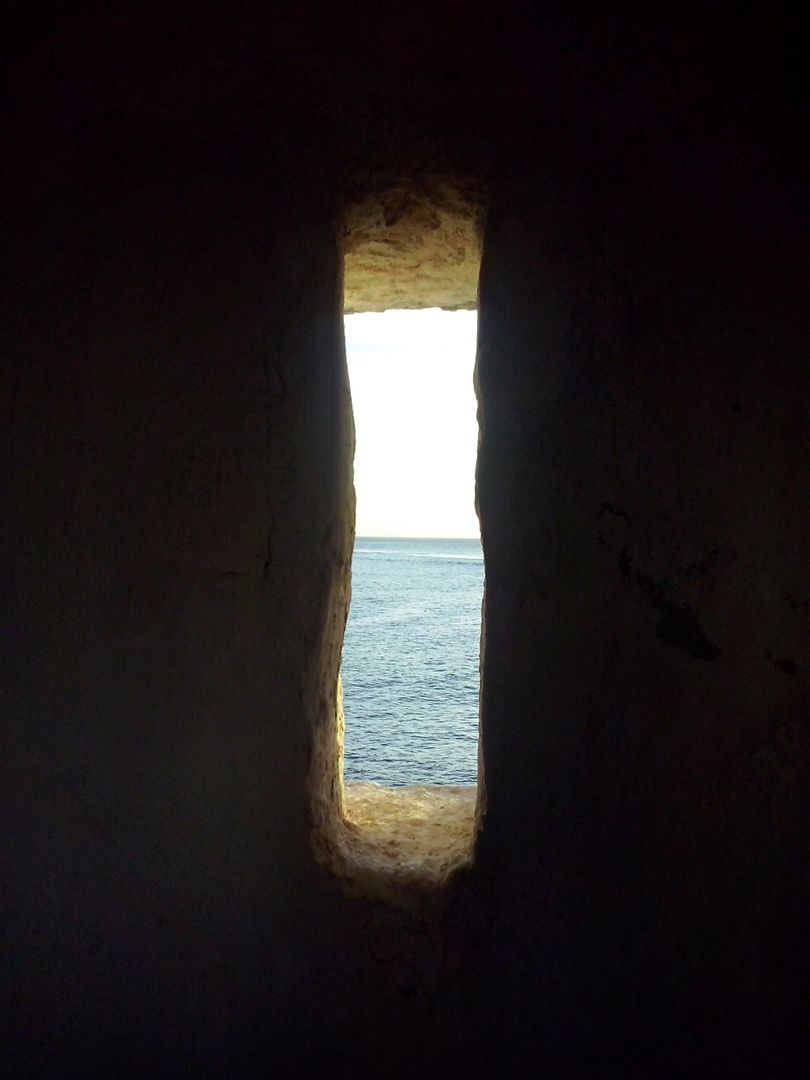 Sunlit Ocean View Through Narrow Stone Window - Free Images, Stock Photos and Pictures on Pikwizard.com