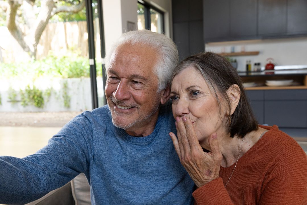 Senior Couple Smiling and Watching Videos on Smartphone at Home